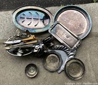 Overview of the lot showing all the silver plated utensils and serving pieces including trays, bowls, and a collection of forks, spoons, and knives.