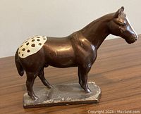 Front side view of brown metal Appaloosa horse figurine with white spotted saddle pattern on a rectangular base.