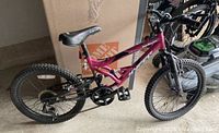 Side view of pink Hyper mountain bike showing 20-inch knobby tires, full suspension, black AirWalk replacement seat, and basic components.