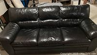 Front view of black leather couch with three seat cushions and three back cushions.