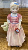 Front view of Royal Doulton porcelain figurine 'Tinkle Bell' showing detailed facial features and attire in pastel pink and blue colors.