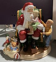 Front view showing Santa with two children seated in green chair and base with toy bag