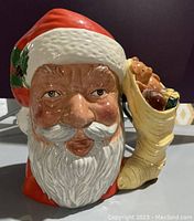 Front view of the Santa Claus Toby jug showing facial details and gift sack handle with teddy bear and gifts.