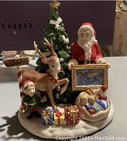 Front view of the Royal Doulton Santa's World Map figurine showing Santa, reindeer, elf, Christmas tree, sleigh with teddy bears, and presents on a snowy base.