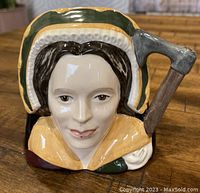 Front view of Royal Doulton Toby Jug depicting Catherine Howard, showing detailed facial features and axe-shaped handle