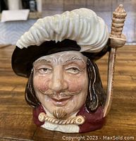 Front view of Royal Doulton Toby Jug depicting Porthos with detailed face, hat with large feather, and sword on side.