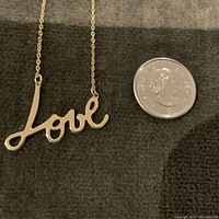 Necklace laid flat next to a quarter for scale showing overall length and pendant size