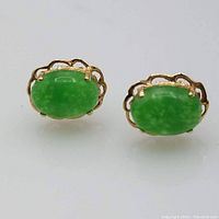 Close-up view of front of the 14K yellow gold earrings showcasing oval polished green jade stones with scalloped gold bezel setting.