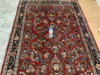 Full view of carpet with water bottle for scale showing red field and navy border