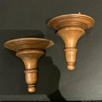 Two vintage teak wall shelves photographed from above, showing circular stepped platforms and turned supports