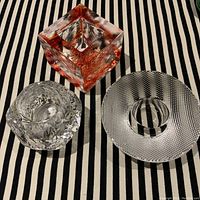 Photo showing all three votive holders on a black and white striped cloth, including the red square holder, clear textured snowball, and clear dotted holder.
