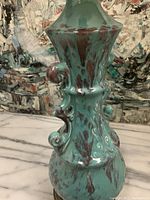 Close-up of ceramic lamp body showing turquoise and brown mottled glaze and sculptural details.