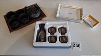 Full lot overview showing cast iron teapot and cups on wooden tray, boxed ceramic sake set and sushi plates.