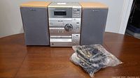 Sony portable stereo and two speakers displayed on wood table along with power cables in plastic bag