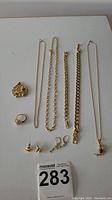 Top view of all jewelry laid flat including two long chain necklaces, two bracelets, one large floral brooch, one ring, two types of earrings pairs including clip-on hoops and twisted knot studs, and a pendant necklace.