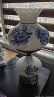 Full image of vintage ceramic tri-lamp showing white ceramic base and floral hand-painted blue design on body and shade