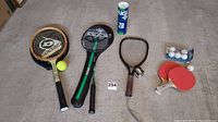 Overview of the lot showing all racquets, paddles, balls and covers arranged on floor.