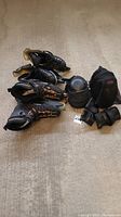 Photo showing men's CCM ice skates size 7, K2 roller blades size 9.5, and various black protective pads including knee, elbow, and wrist protection all laid out on a concrete floor.