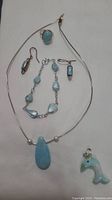 Full view of all items: necklace with pendant, ring, bracelet, two earrings, and dolphin pendant.