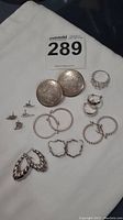 Full lot displaying all silver jewelry pieces on a white cloth background showing various earring pairs and the ring.