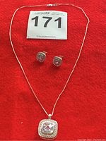 Sterling silver 18-inch chain necklace and matching earrings laid flat on a red fabric background displaying the set clearly