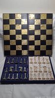 Full view of open chess set with playing board and organized onyx pieces in fabric-lined compartments