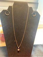 Full view of necklace with pendant and matching circular hoop brooch on black necklace stand