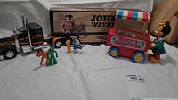 Full set of vintage toys including Mickey's Corn Popper, John Wayne truck, Handy Smurf, Gumby and Pokey figurines on white background.