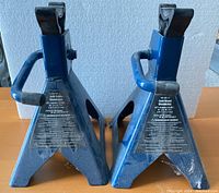 Photo of two blue metal axle stands placed side by side showing front and handles.
