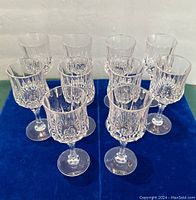 Front view of ten crystal stemmed glasses showing six tall and four shorter glasses with faceted cut design on bowls.