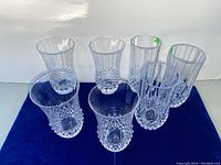 Seven clear tumblers in two styles, some with small chips visible.