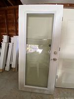 Front view of the white exterior glass door with full glass panel, showing slight dirt on bottom and reflections in the glass.