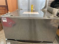 Front view of LG dryer pedestal showing metal housing and mounting brackets