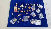Overview of all pins laid out on a blue velvet background, showing assortment and variety