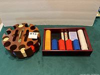 Photo showing wooden round swivel caddy with compartments filled with multi-colored poker chips and rectangular box containing poker chips, two decks of cards, and dice.
