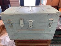 Front view of the vintage blue steamer trunk with metal locks and handles.