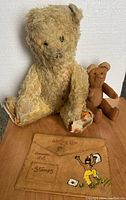 Photo showing the two vintage bears sitting on a wooden surface along with the vintage cowhide writing pouch laid flat in front.
