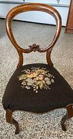 Front view of vintage open back wooden chair with floral petit point upholstery on seat