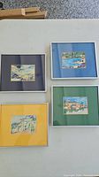 Four framed watercolour and ink paintings on table, different colored mats