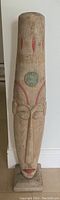 Full front view of the tall carved wooden statue showing elongated face and painted features