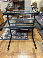 Overview of assembled black metal frame desk with glass surfaces in living room setting.