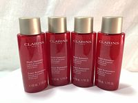 Four bottles of Clarins Multi-Intensive Super Restorative Treatment Essence 50ml each in red plastic bottles with silver caps.