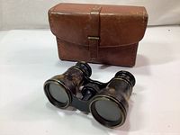 Antique Lemaire Paris opera glasses with original brown leather case behind.