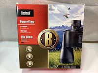 Front of sealed box with Bushnell branding and product image showing black binoculars, product name, power and objective lens size.