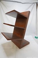 Full view of the handmade wooden shoe stand showing three angled shelves and solid base with vertical back panel