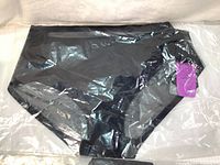 Sealed black Knix Luxe boyshort underwear in original plastic packaging showing front side.