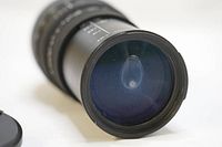 Close-up of front element of Sigma telephoto zoom lens showing moisture inside the glass surface.