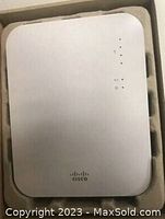 Top view of white Cisco Meraki MR16 wireless access point inside original packaging showing Cisco logo and status indicator LEDs.