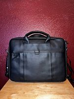 Front view of black Dell leather laptop briefcase with dual handles and small flap pocket on front.