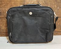 Front view of black Dell laptop carrying case showing zippered front pocket and Dell logo button.